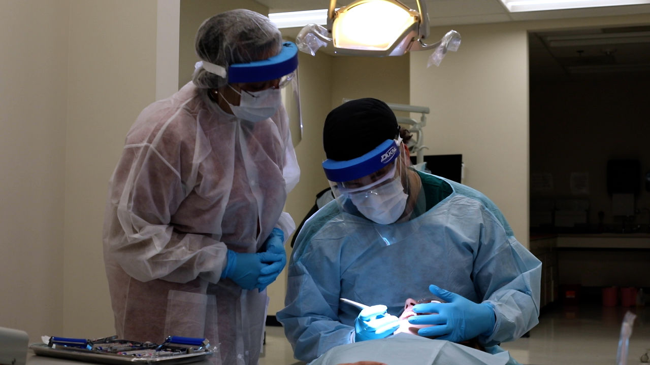 Dental professionals performing procedure in clinic setting