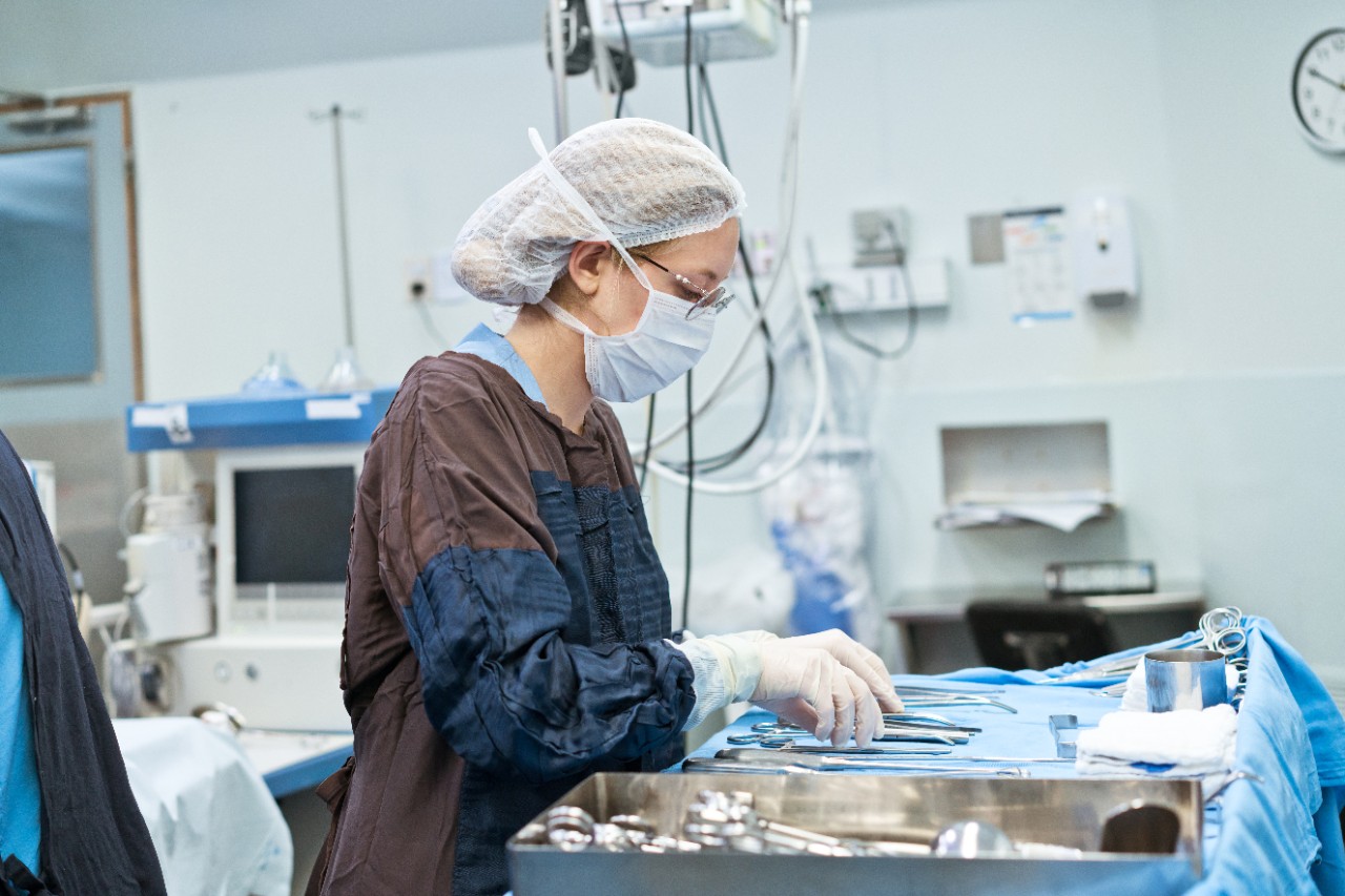 Female nurse with surgical equipment on tray in operating room at hospital