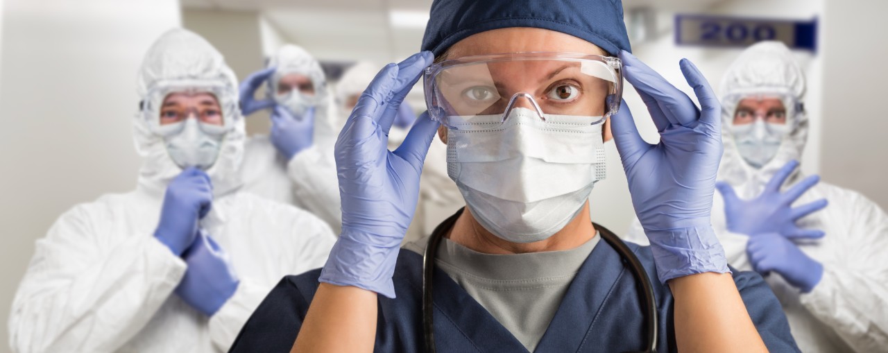 Team of Female and Male Doctors or Nurses Wearing Personal Protective Equiment In Hospital Hallway.