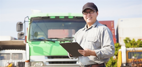Worker with clipboard near green truck