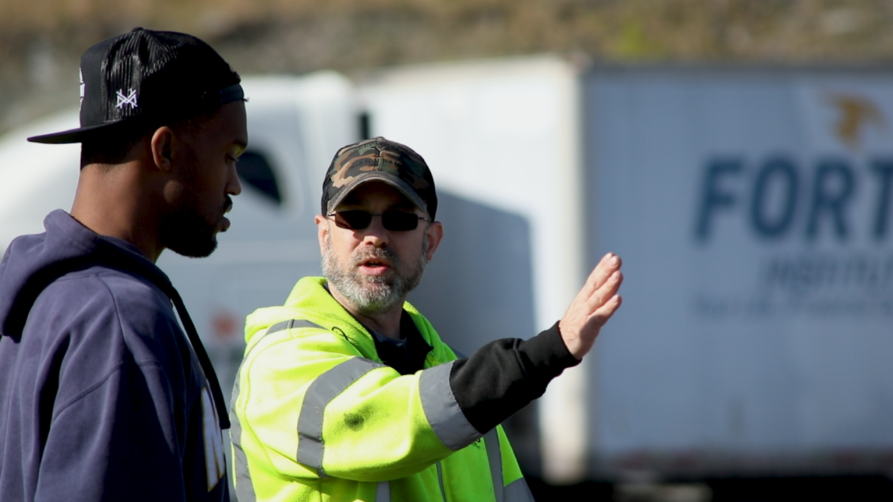 Two men in discussion near industrial truck outdoors