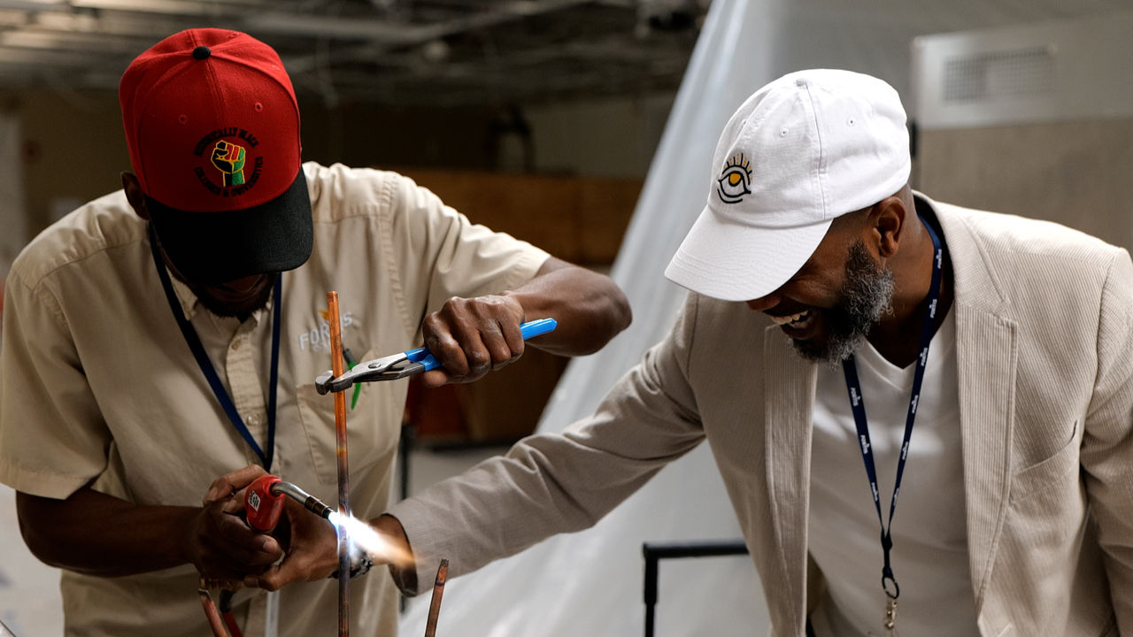 Two men collaborate on hands-on metalworking project