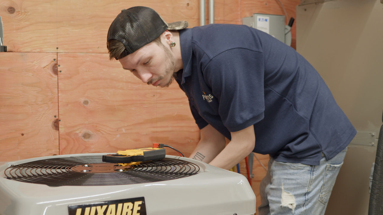 Technician servicing Luxaire HVAC unit indoors
