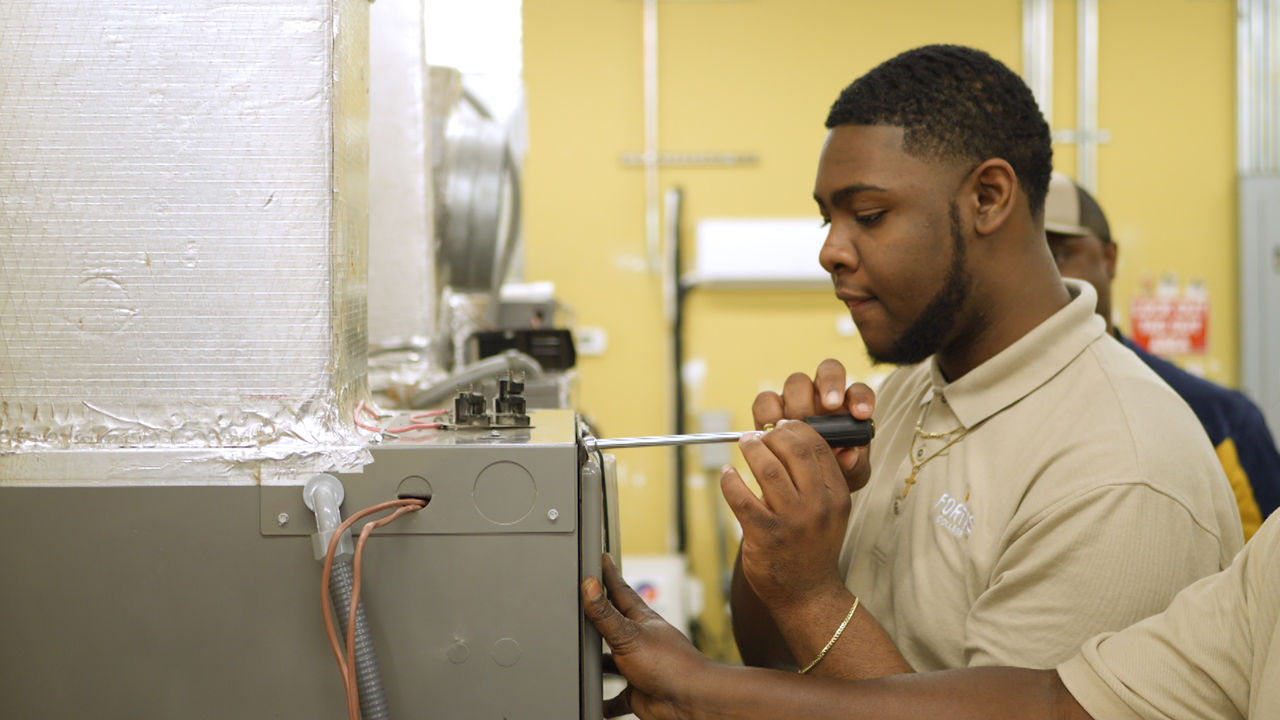 Technician repairing industrial HVAC unit with screwdriver