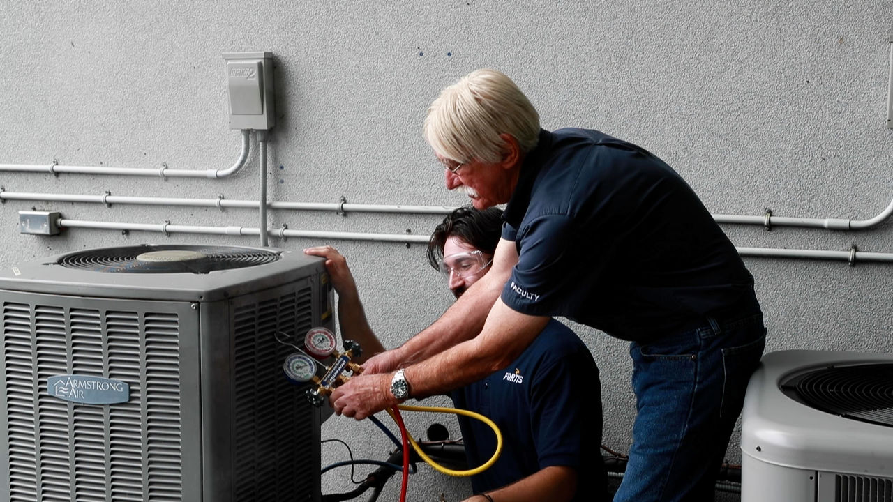 Technicians servicing Armstrong air conditioning unit outdoors