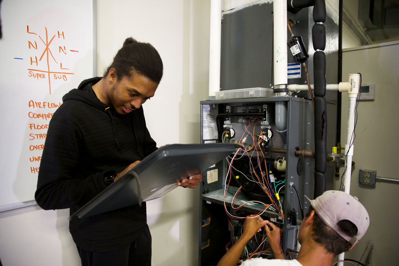 Technicians Repairing HVAC System in Workshop Setting