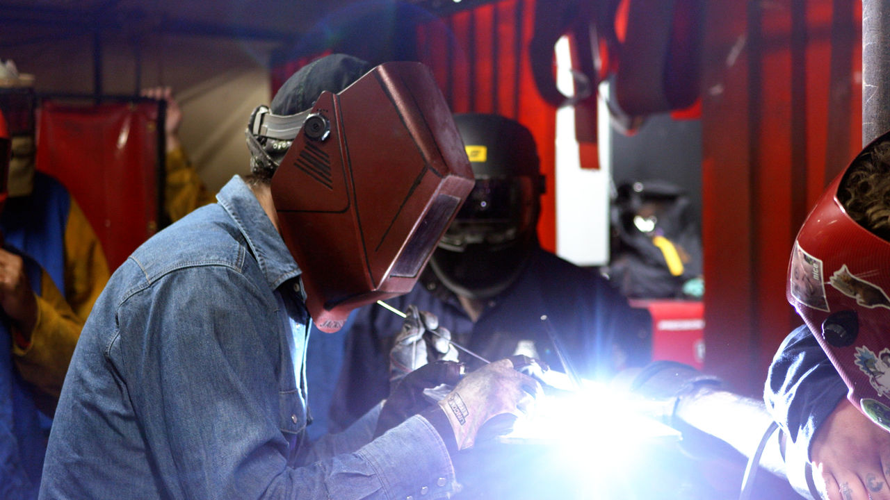 Industrial workers welding metal in workshop setting